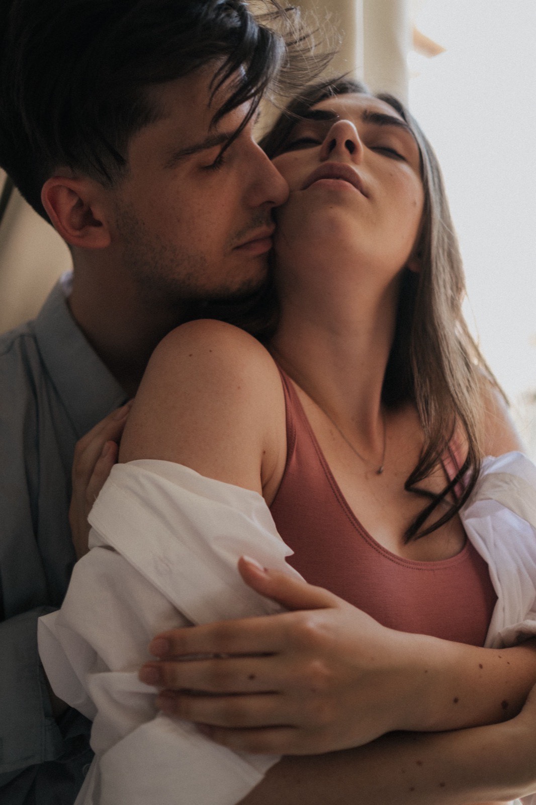 Couple in a close embrace by a bright window
