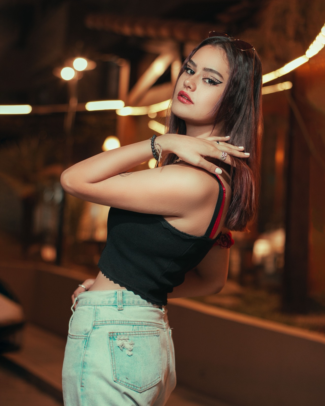 Woman looking back at night with warm city lights behind her