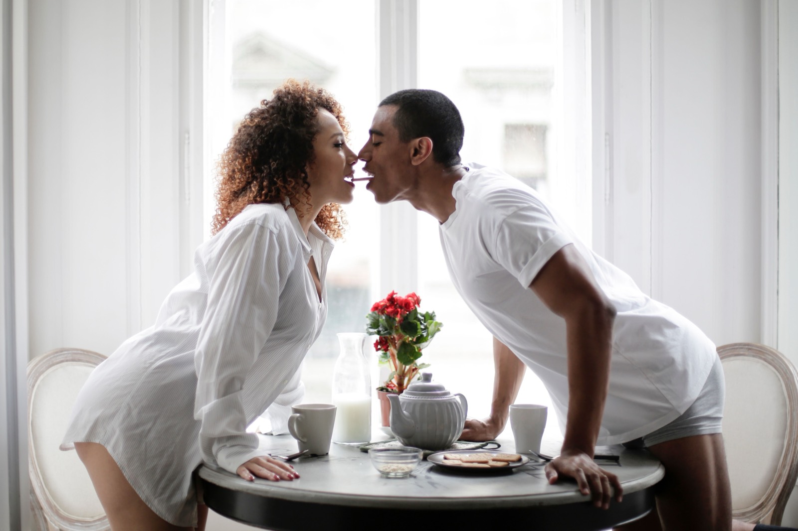 Couple sharing breakfast across a table by bright windows